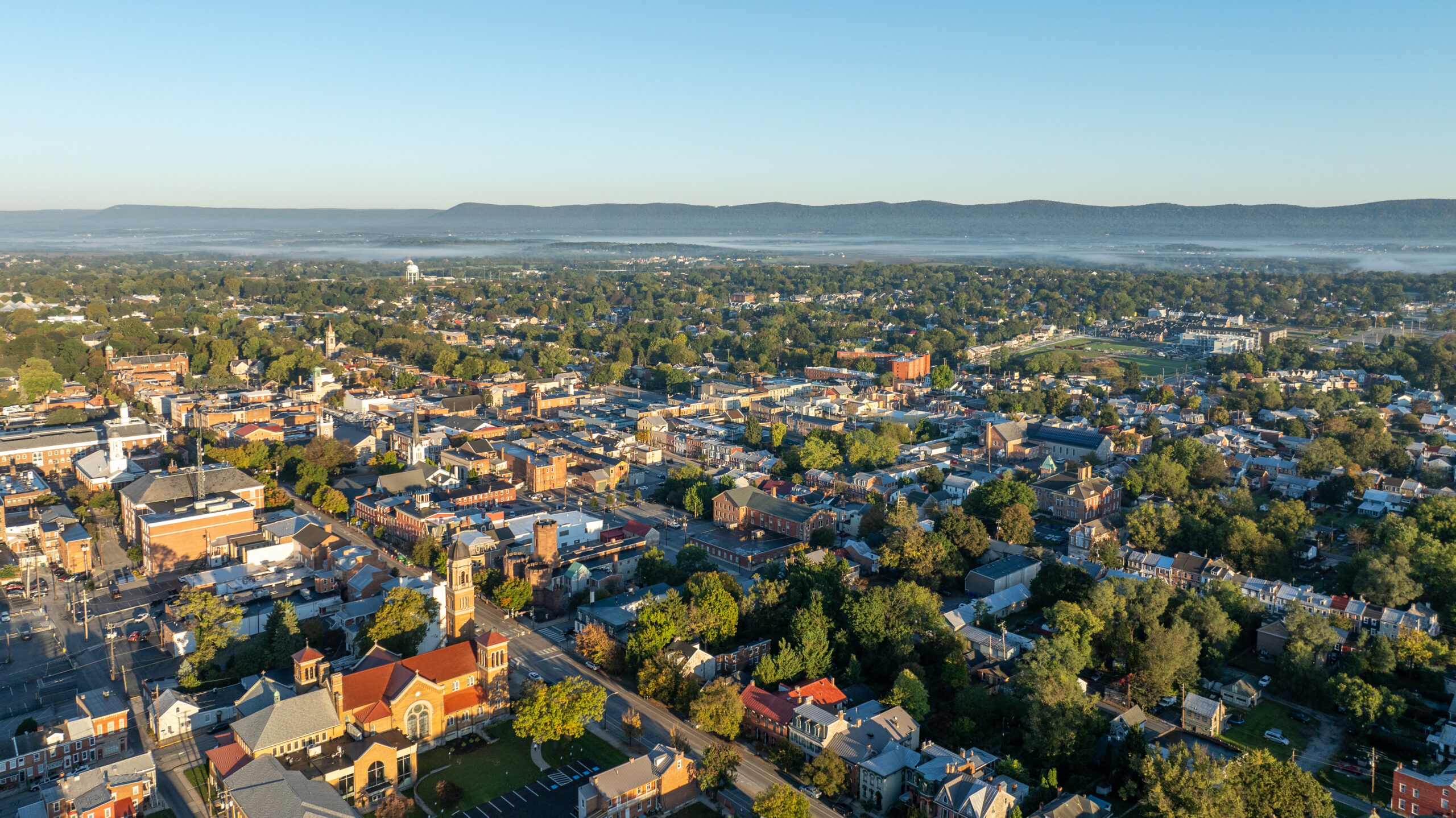 Aerial view of Carlisle, Pennsylvania, featuring a mix of historic buildings, residential areas, and tree-lined streets on a clear day.